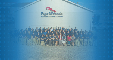 A celebratory group photo of the Pipe Wrench Plumbing team marking a company anniversary