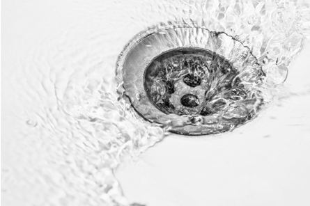 Water flows freely down a drain in a white sink