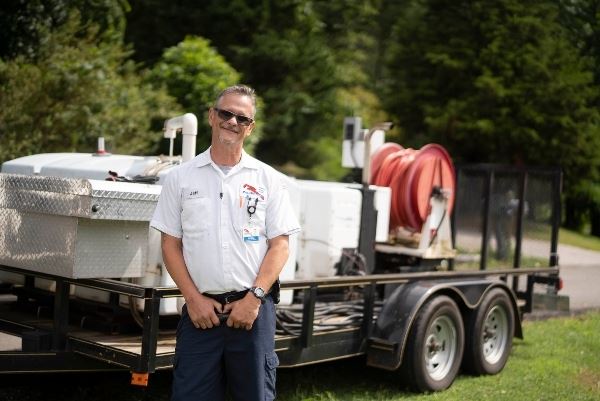Jeff Allen smiling with sewer line equipment trailer