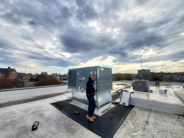 HVAC technician inspecting a rooftop commercial air conditioner