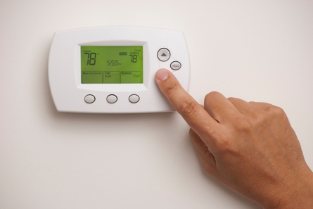 Digital thermostat with a hand lowering the temperature
