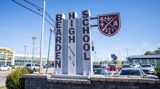 Vertical sign for Bearden High School on side of a road.