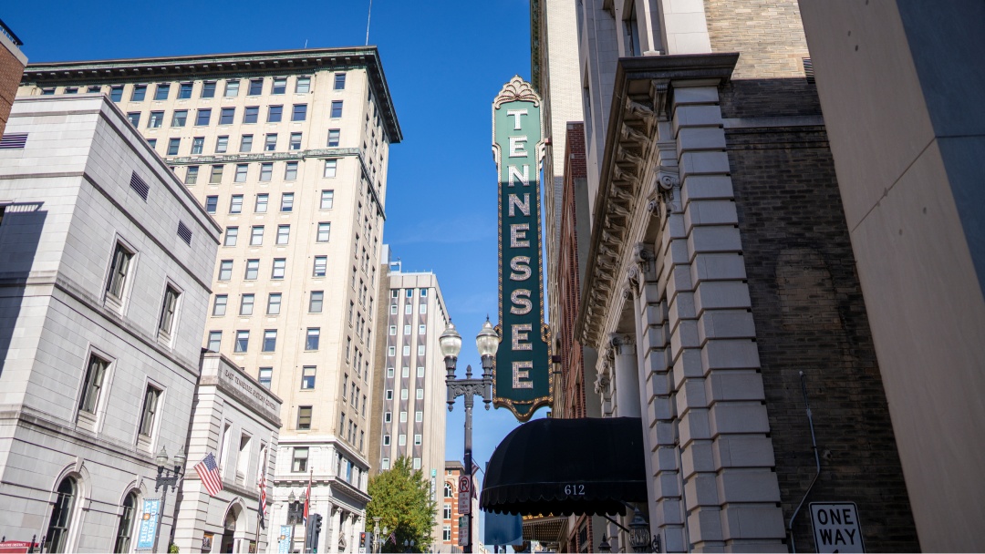 View of tall buildings in a city, with vertical sign in foreground that says "Tennessee"