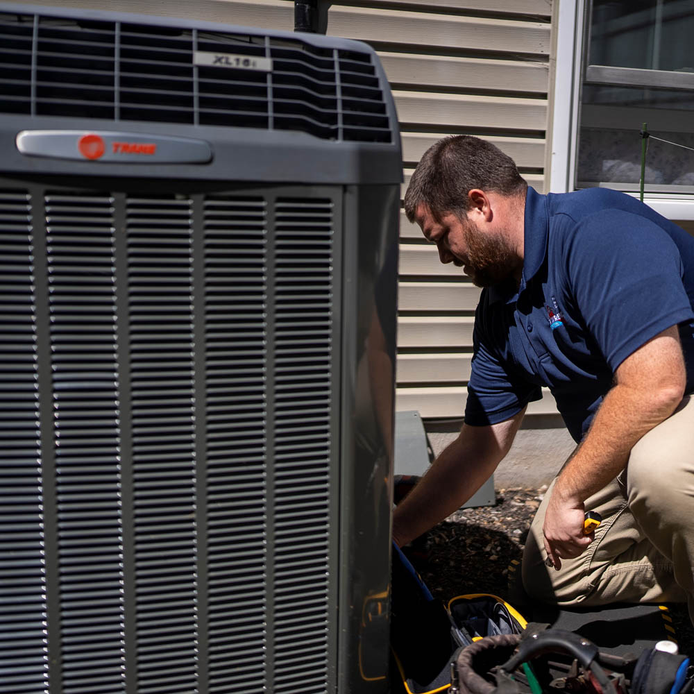 Technician repairing an HVAC unit outside a home