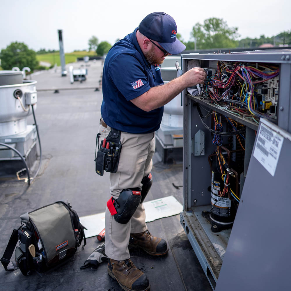 Pipe Wrench technician repairing a commercial HVAC system installed on a roof.