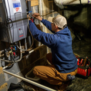 Plumber repairing a water heater in a home's basement.