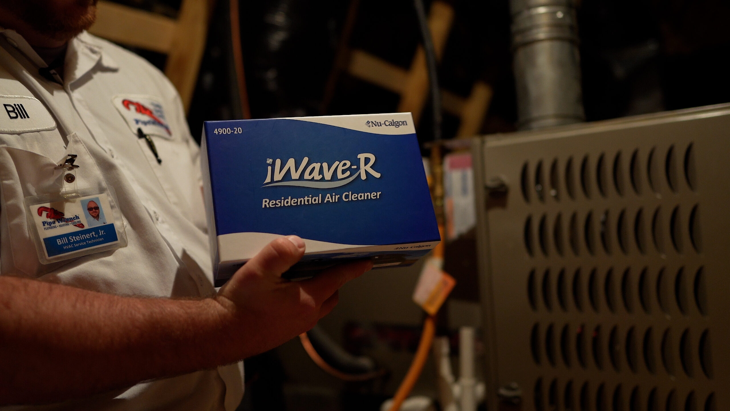 Technician holding iWave air cleaner box in front of HVAC unit