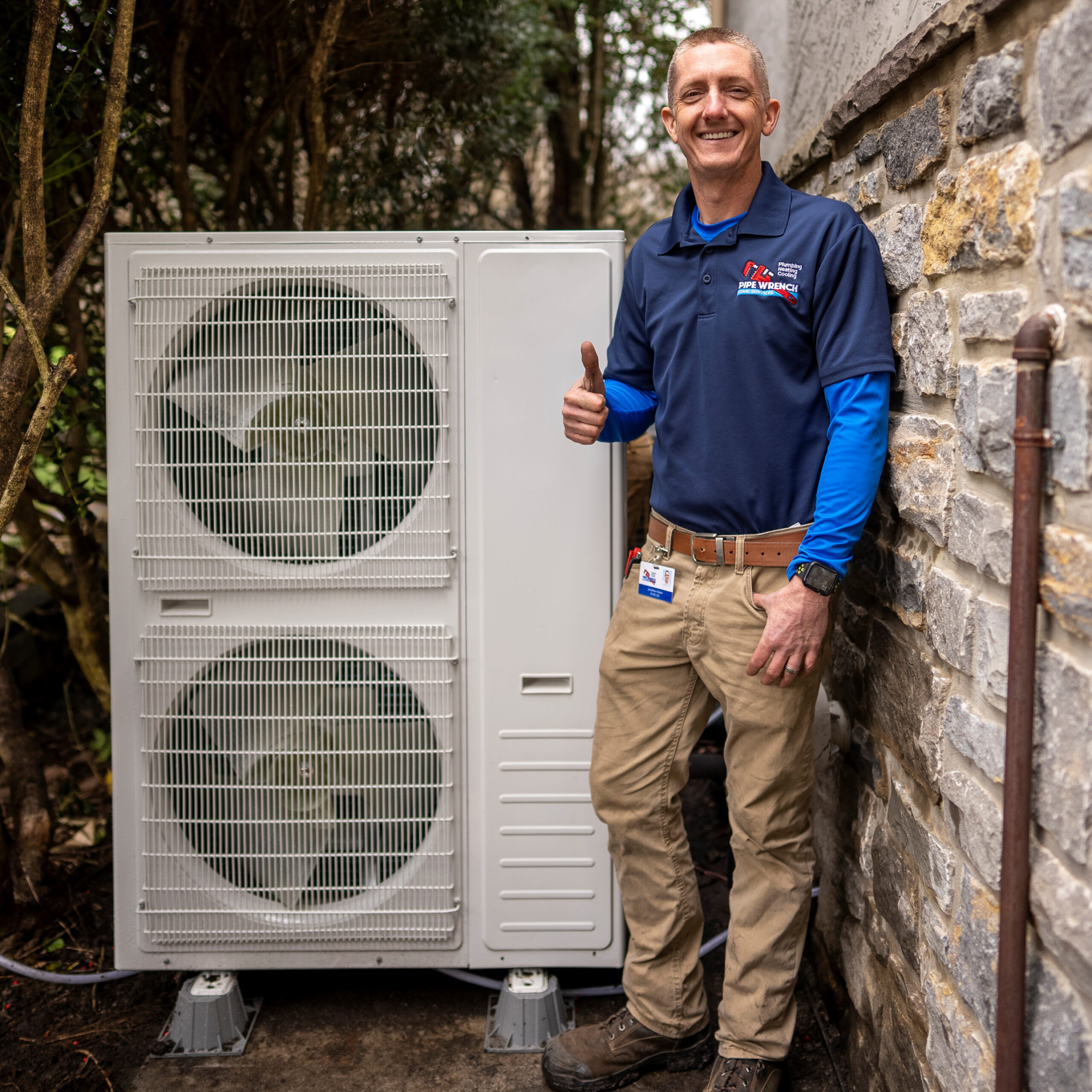HVAC technician smiling and giving thumbs up while standing next to a Keiser double-stacked discharge unit installed next to a home.